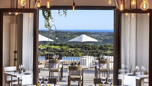 An outdoor dining area with tables and chairs, overlooking a scenic landscape. - Relais Chiaramonte (Ragusa)