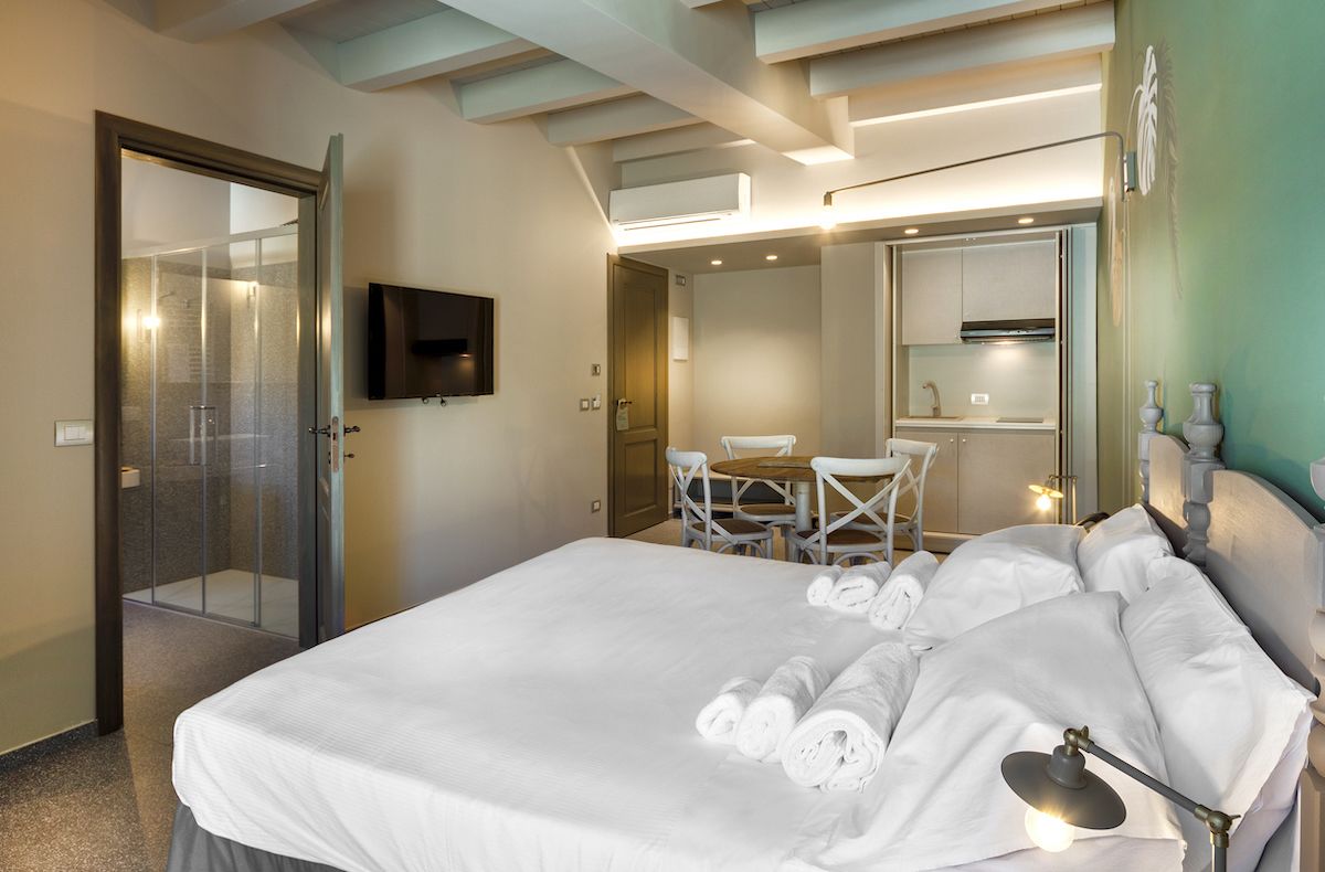 A hotel room with a large bed, a desk, and a shower area.