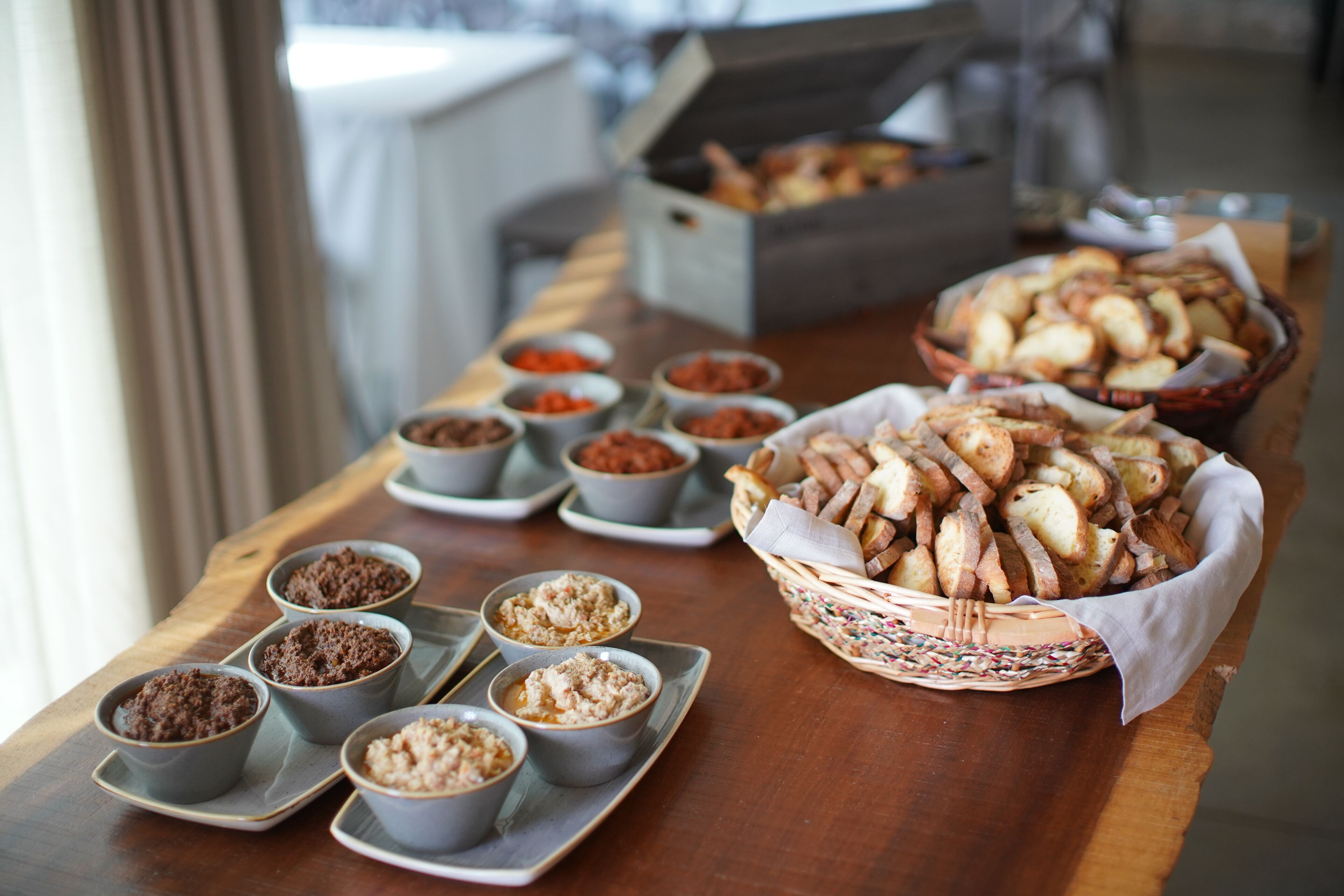 A buffet table with various food items including bread, dips, and desserts.
