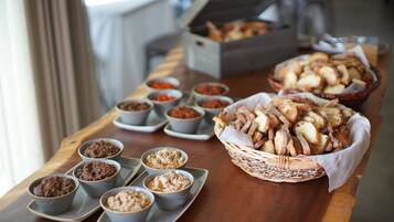 A buffet table with various food items including bread, dips, and desserts.