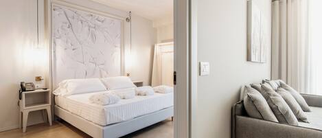 Quarto moderno com cama, mesas de cabeceira e um sofá.