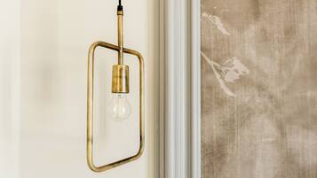 Un luminaire suspendu, de type suspension, avec un cadre en laiton et une ampoule en verre transparent, le tout suspendu à un cordon noir.