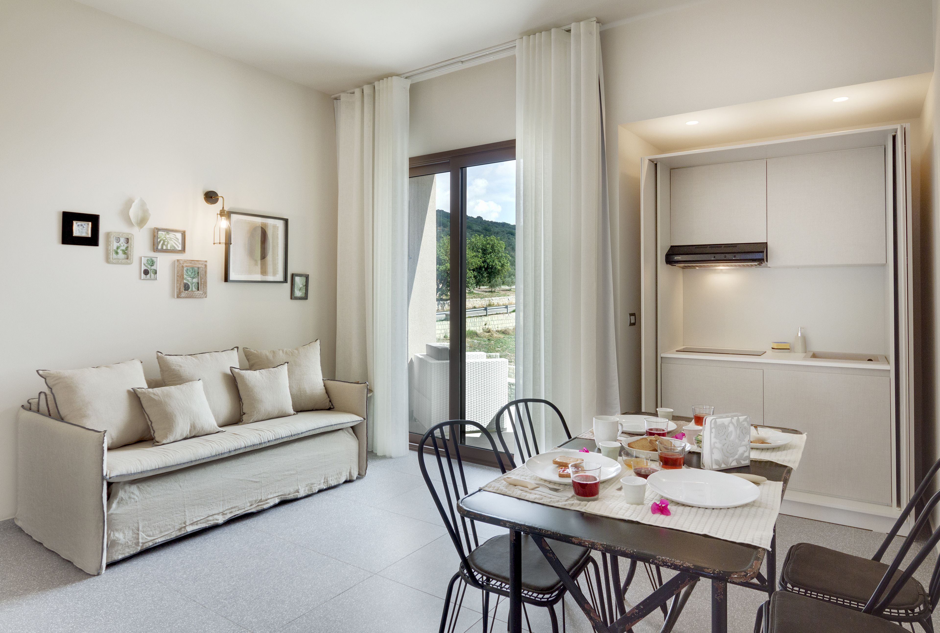 Un comedor moderno con sofá, mesa, sillas y vistas al exterior.
