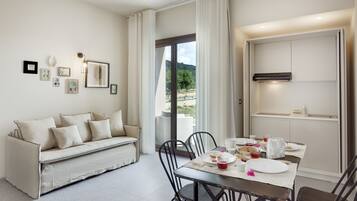 A modern dining area with a sofa, dining table, chairs, and a view of the outdoors.
