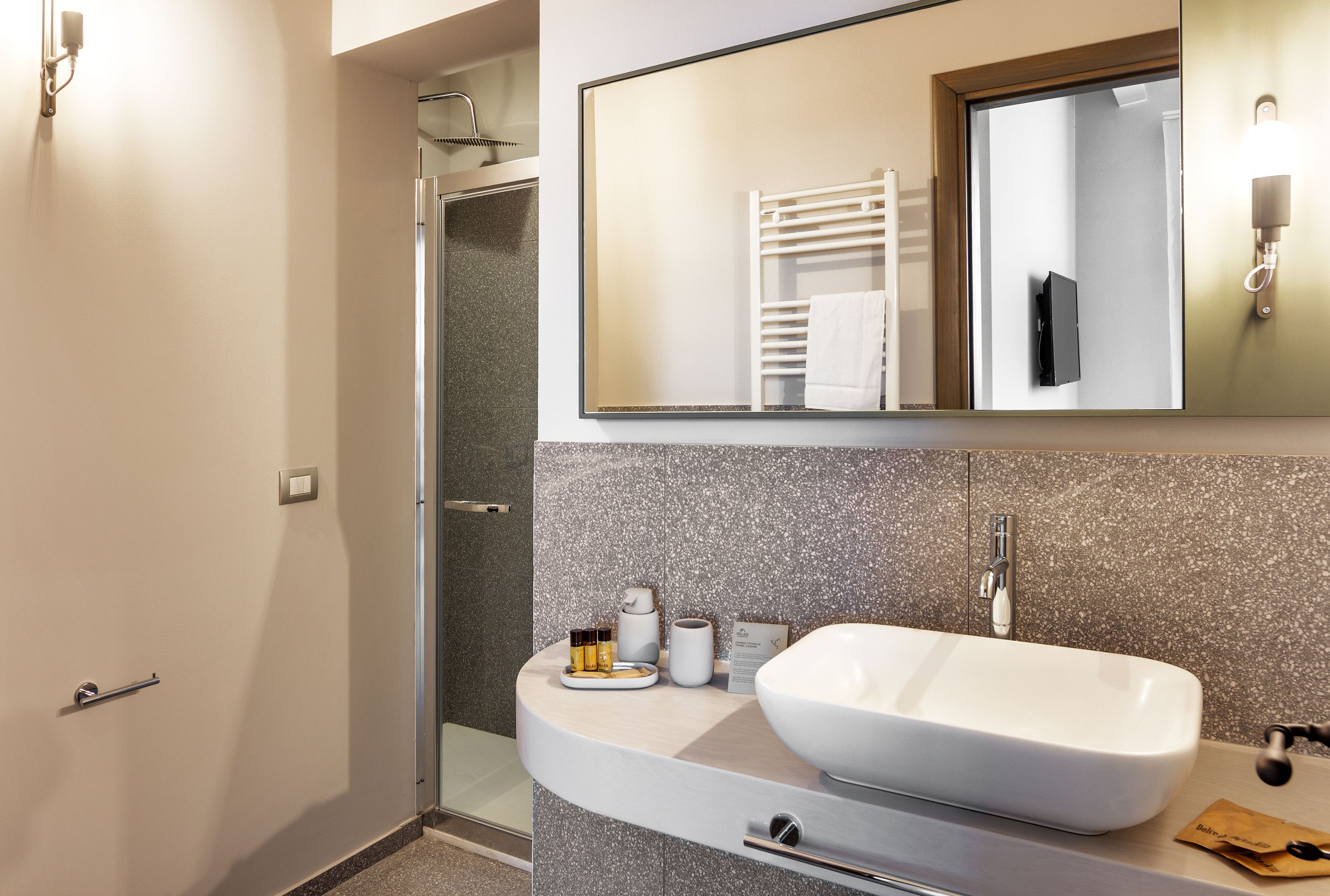 Un baño moderno con un lavabo grande, un espejo y una zona de ducha.