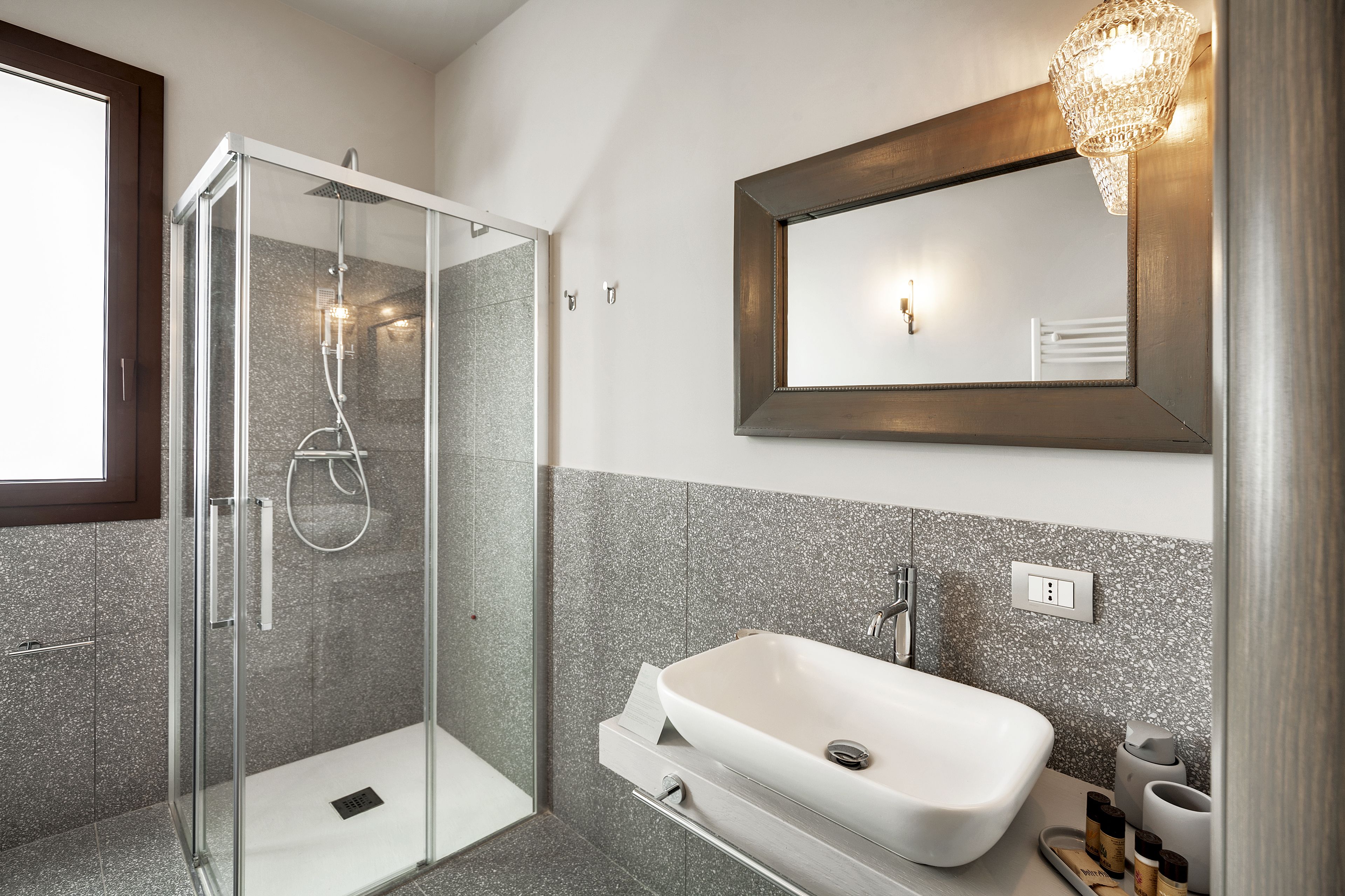 A modern bathroom with a glass-enclosed shower, a white sink, and a mirror with a wooden frame.