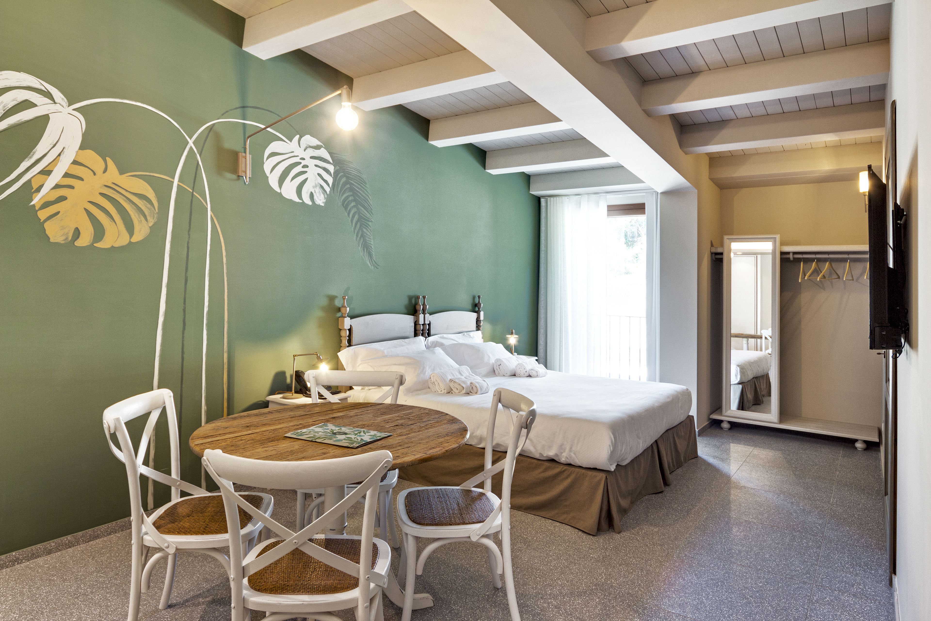 A bedroom with a bed, bedside tables, a mirror, and a window.