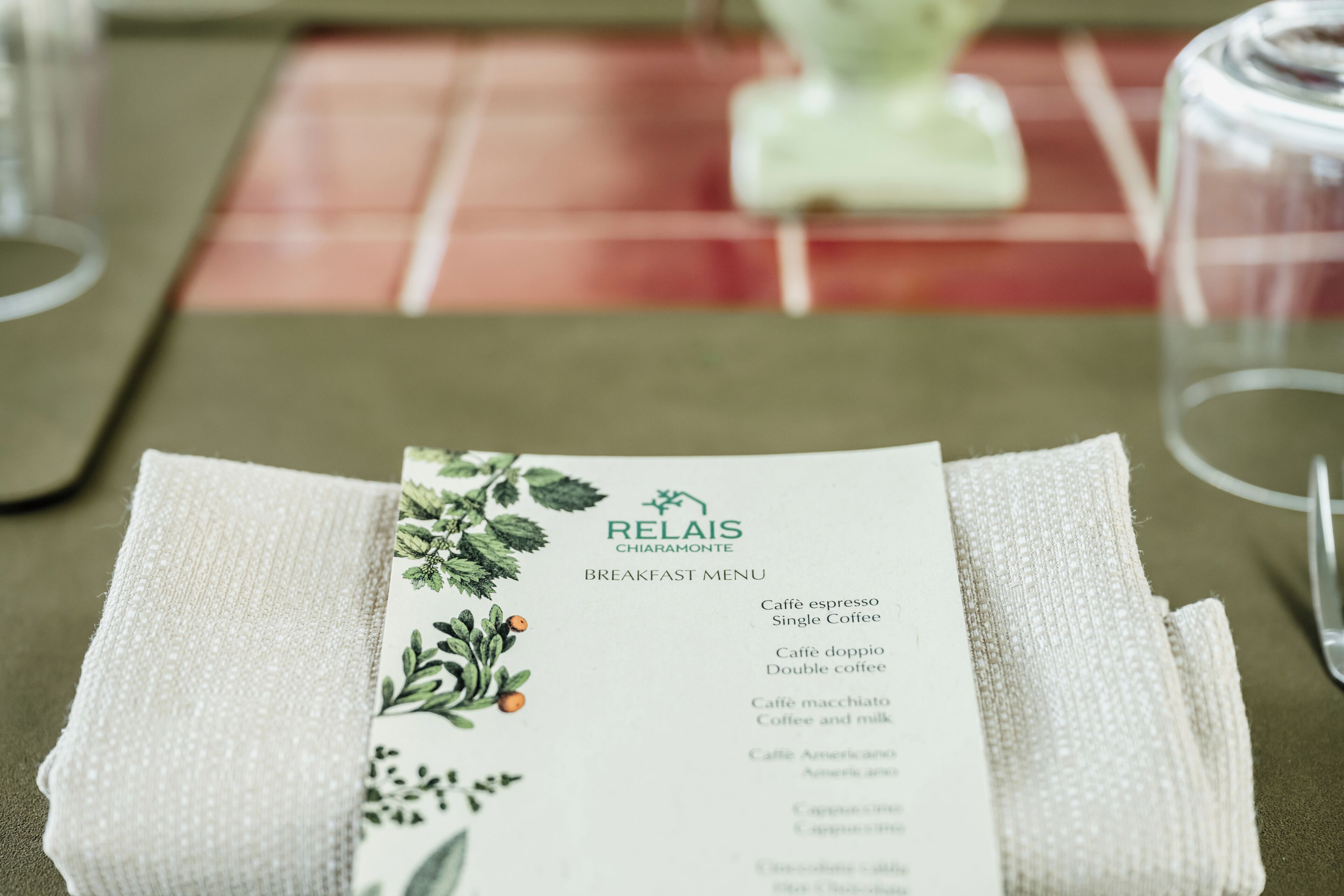 Un menú de desayuno doblado cuidadosamente sobre una mesa con un posavasos verde.