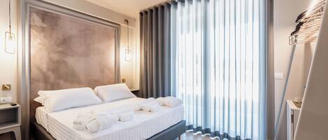 Une chambre d’hôtel moderne avec un grand lit, une table de chevet et une grande fenêtre avec des rideaux.