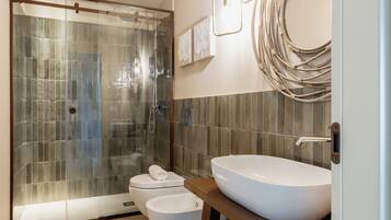 A modern bathroom with a glass-enclosed shower, a white sink, and a toilet.