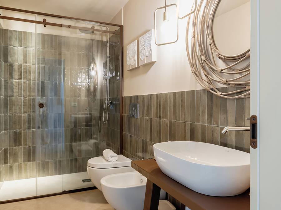 A modern bathroom with a glass-enclosed shower, a white sink, and a toilet.