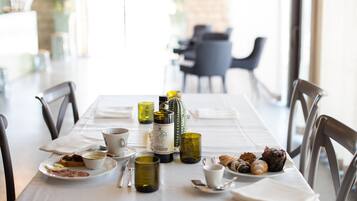 A dining table set with plates, cups, and a bottle, surrounded by chairs in a bright room with a view.