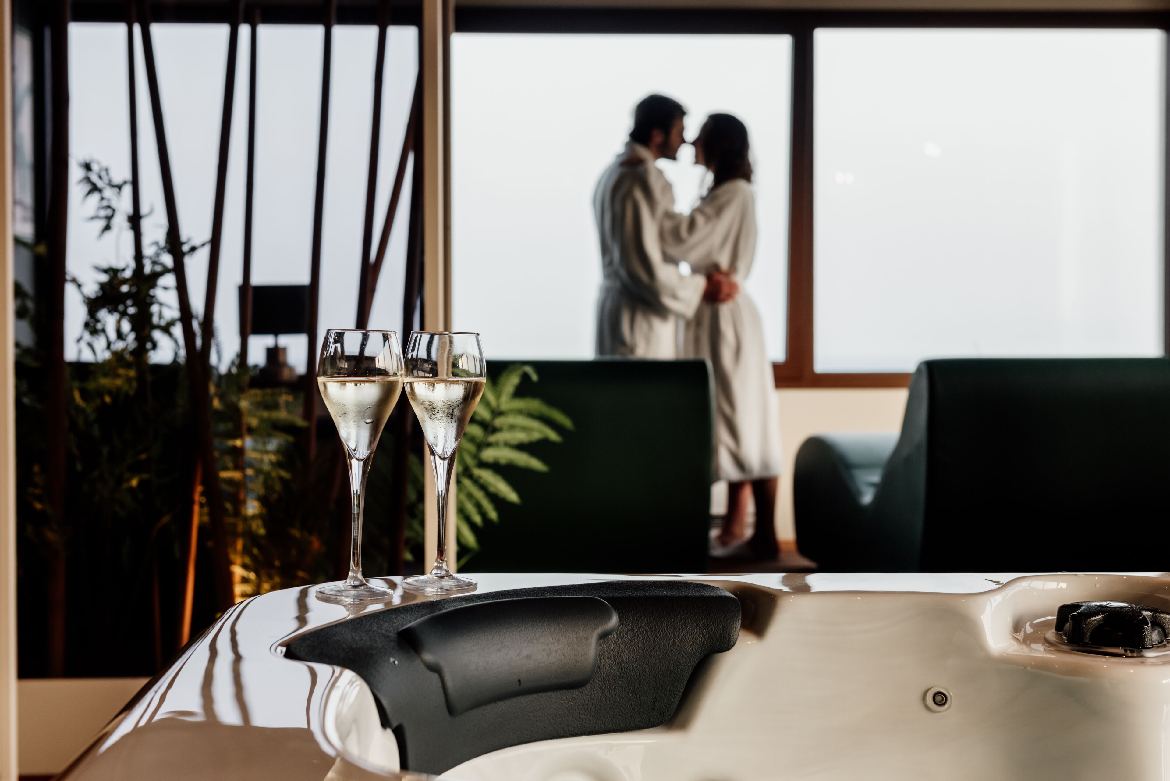 A spa area with a hot tub, two champagne glasses, and a couple in the background.