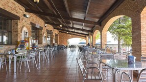 Un café en plein air avec des murs en briques, des chaises et des tables en métal.