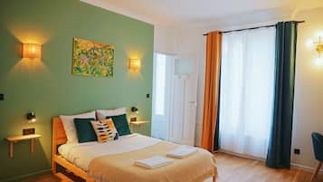 Un dormitorio con cama, mesitas de noche, un cuadro y una ventana con cortinas.