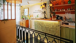 A modern kitchen with a green tiled backsplash, wooden cabinets, and a hanging light fixture. - Maison Coquelin - Adults Only (La Roche-Guyon)