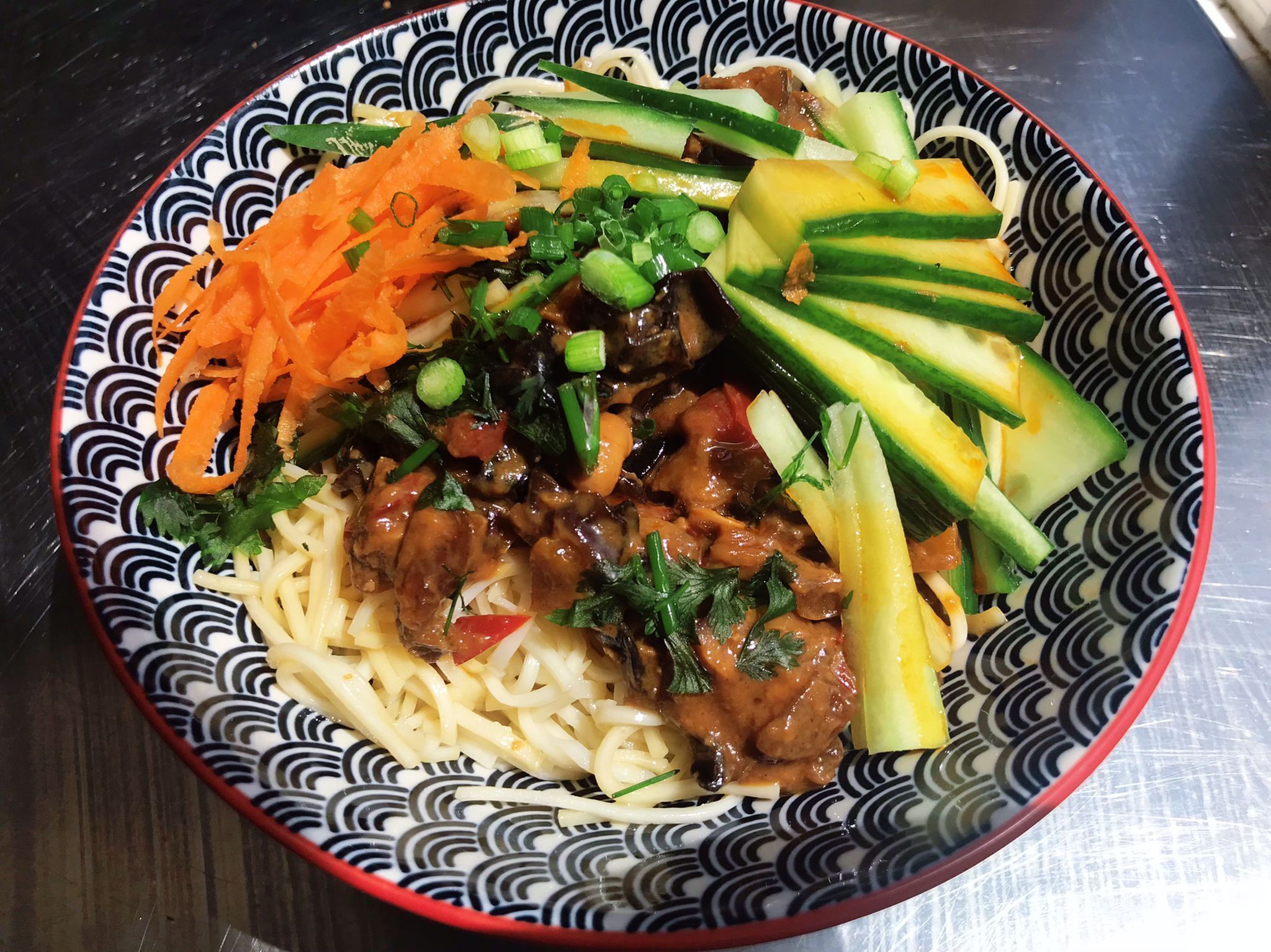 A bowl of noodles with vegetables and meat.