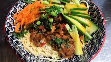 A bowl of noodles with vegetables and meat.