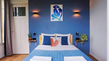 Ein Schlafzimmer mit einem Bett, zwei Nachttischen, einem Wandbild und einem Blumentopf.