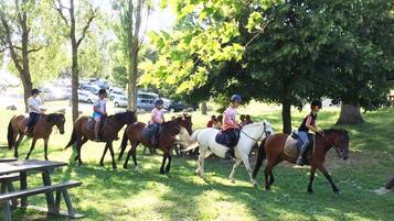 Un grupo de personas montando a caballo en un parque con árboles y una mesa de picnic.