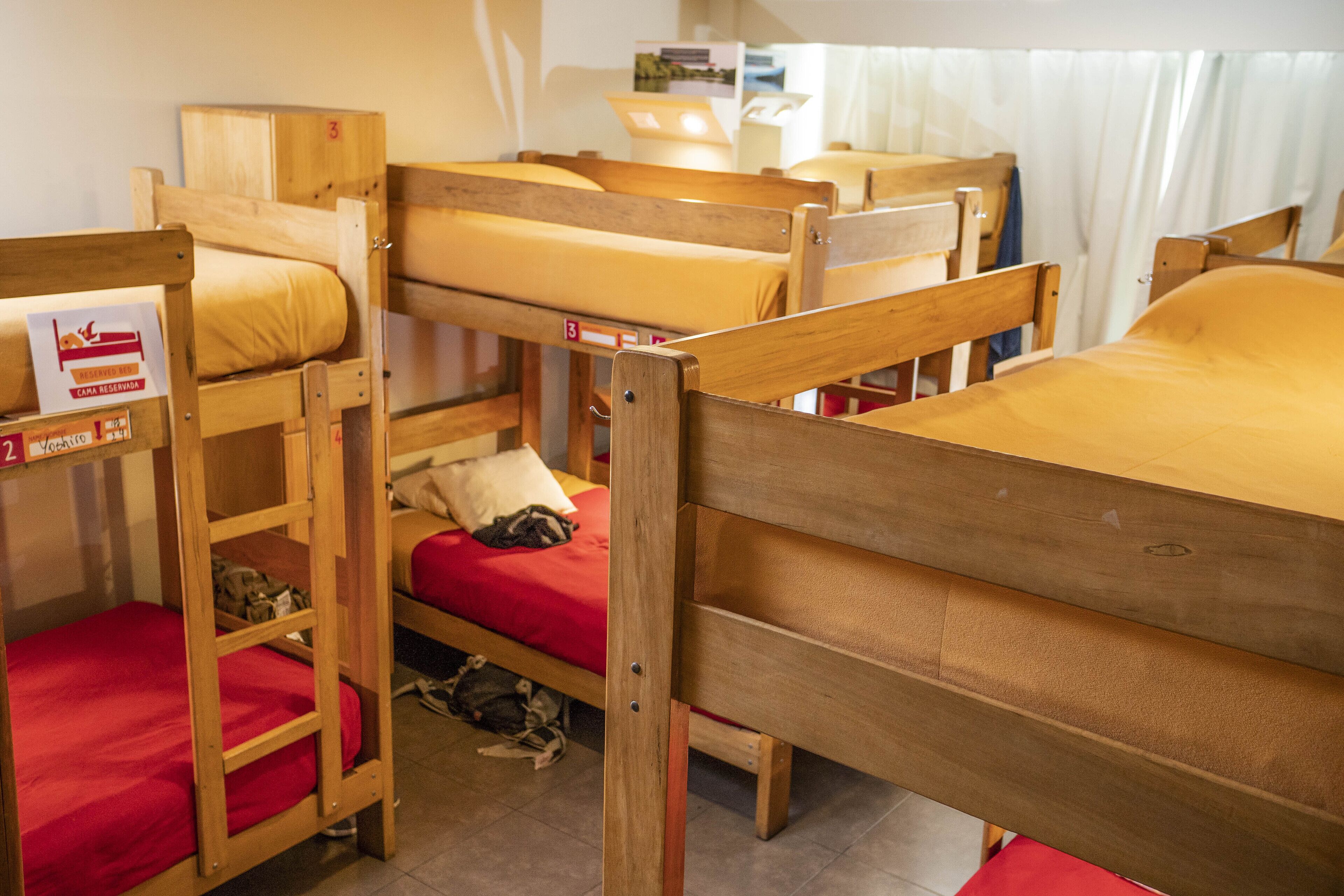 Ein Schlafsaalzimmer mit Etagenbetten, einem kleinen Schreibtisch und einem Fenster mit Vorhängen.