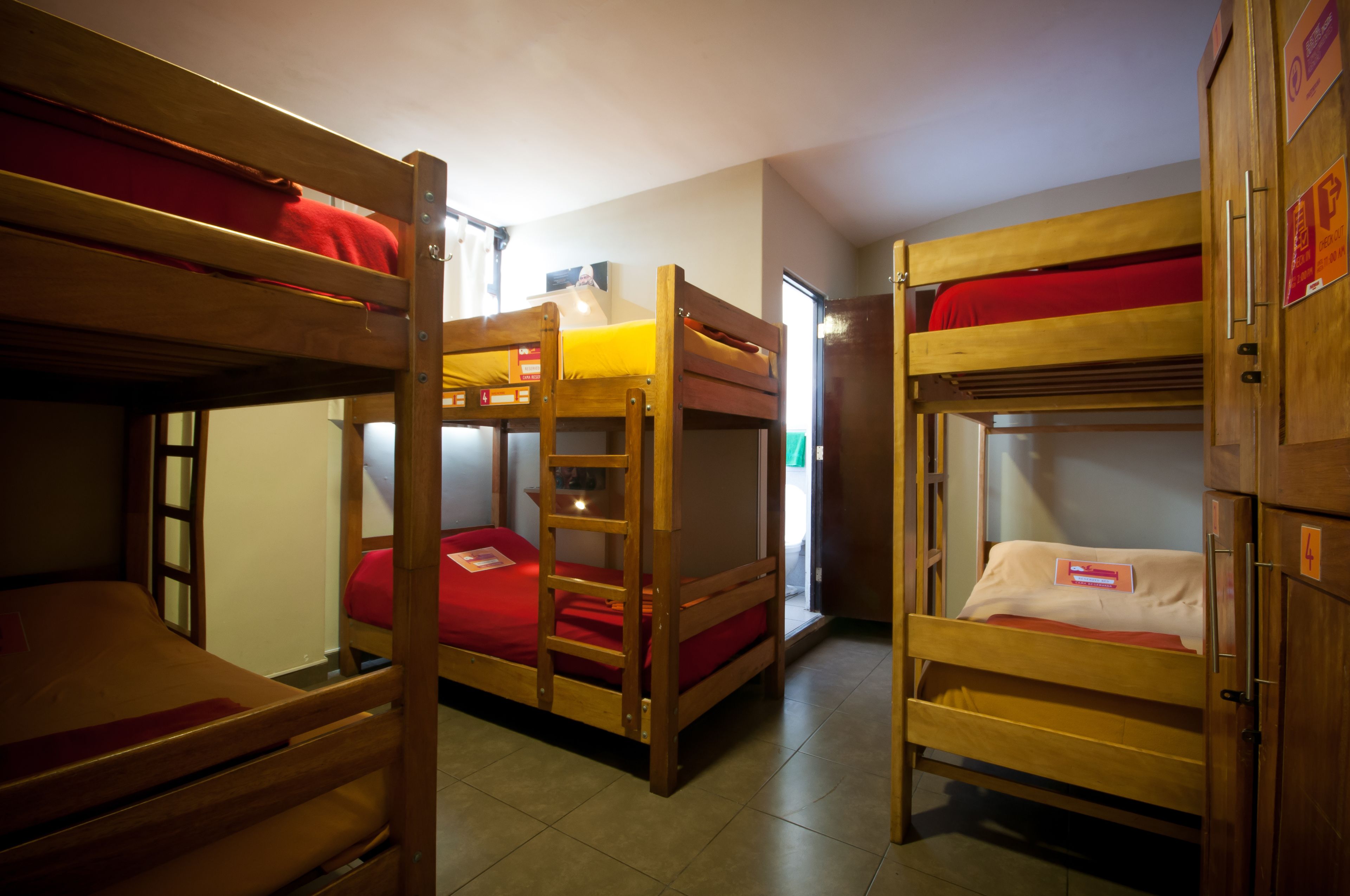 A dormitory room with bunk beds, a wooden wardrobe, and a small table.