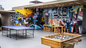 A vibrant indoor space with a ping pong table, foosball table, and a mural-covered wall. - Pariwana Hostel Lima - Adults only (Lima)