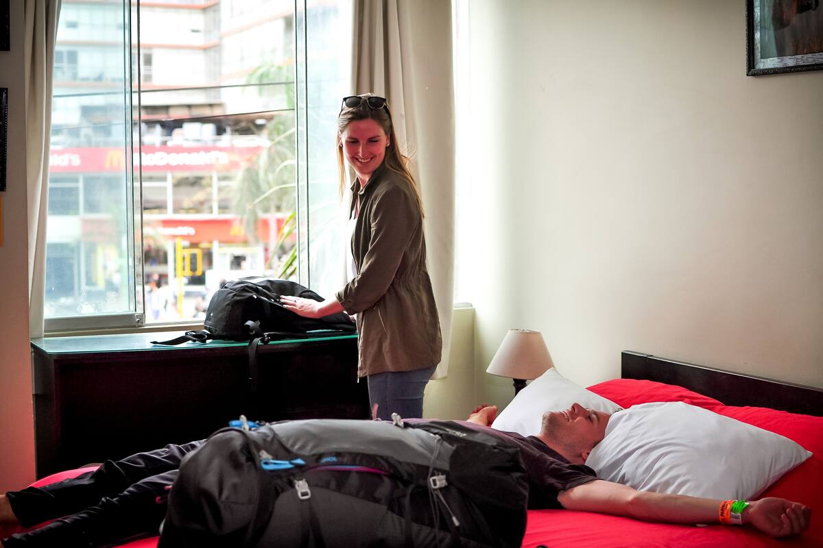 A hotel room with a bed, a window with a view of a McDonald's, and a lamp on the bedside table.
