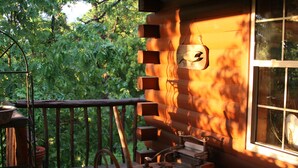 Eine Holzhütte mit Veranda, einem Willkommensschild und einem Fenster mit Blick auf Bäume.