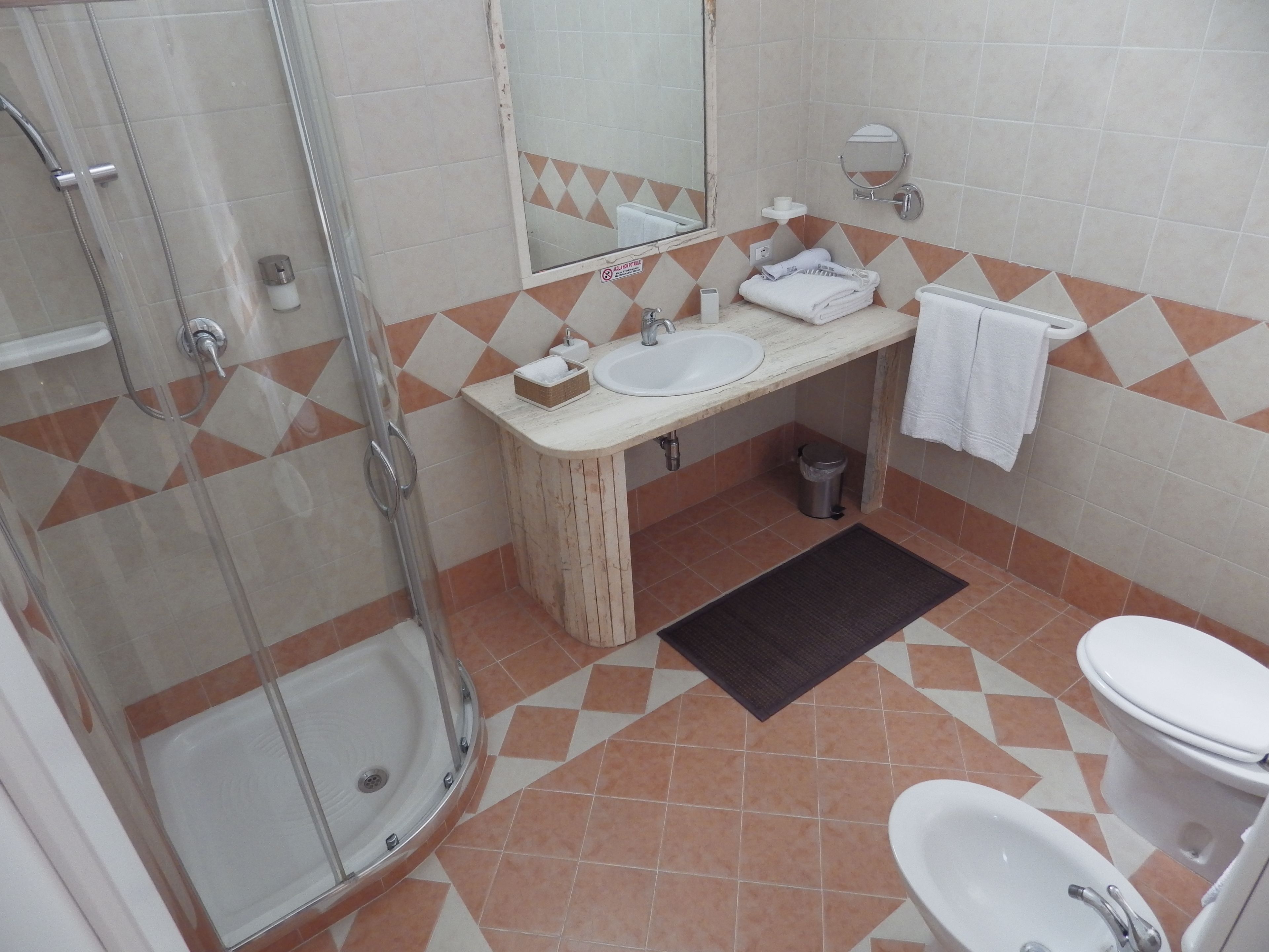 A bathroom with a glass-enclosed shower, a sink, a toilet, and a bidet.
