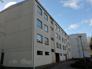 A multi-story building with a flat facade, multiple windows, and a red door. - Scandinavian Sun Apartments (Kotka)
