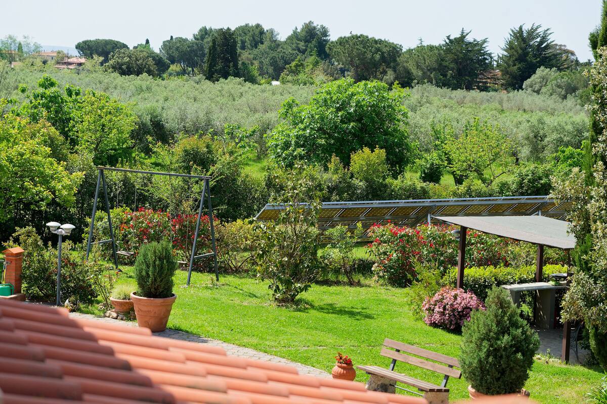 Un jardin doté d’un espace patio, comprenant un banc et une table placés sous une pergola.