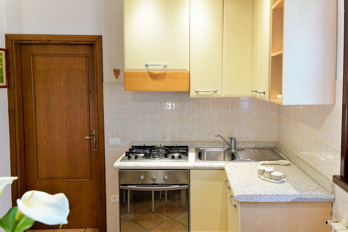 Une cuisine avec une porte en bois, des appareils électroménagers en acier inoxydable et un dosseret carrelé.