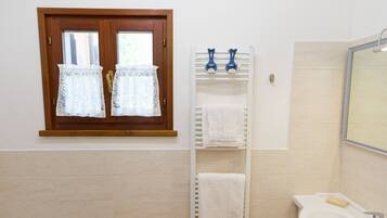 Un baño con ventana de madera, un perchero, un lavabo y un espejo.