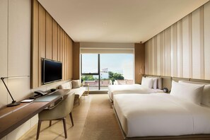 A hotel room with a large bed, a desk with a chair, a TV, and a view of the outdoors. - Joyze Hotel Xiamen Curio Collection by Hilton (Xiamen)