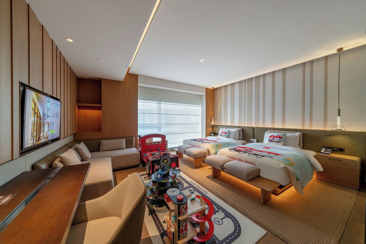 Une chambre d’hôtel avec un canapé, deux lits, un bureau et une tél évision.