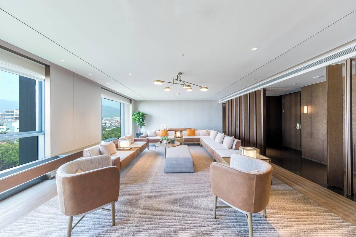 Un hall d’hôtel moderne doté d’un grand espace salon, d’un plafond haut et de grandes fenêtres offrant une vue sur la ville.