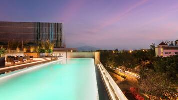 Piscina com espreguiçadeiras e vista para um edifício de design moderno.