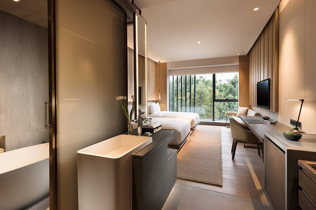 Une chambre d’hôtel moderne dotée d’un grand lit, d’un bureau, d’une salle de bain avec baignoire et d’une télévision.