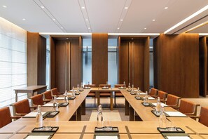 A conference room with long tables, chairs, and water bottles. - Joyze Hotel Xiamen Curio Collection by Hilton (Xiamen)