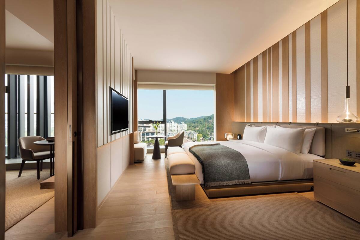 Une chambre d’hôtel moderne dotée d’un grand lit, d’une télévision, d’un bureau et offrant une vue sur la ville.