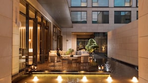 A modern hotel lobby with a seating area, a water feature, and a view of the building's exterior. - Joyze Hotel Xiamen Curio Collection by Hilton (Xiamen)