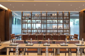 A modern dining area with long tables, chairs, and a large display of decorative items. - Joyze Hotel Xiamen Curio Collection by Hilton (Xiamen)