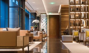 A modern hotel lobby with a seating area, a reception desk, and a bookshelf. - Joyze Hotel Xiamen Curio Collection by Hilton (Xiamen)