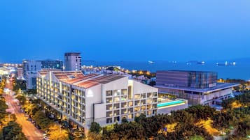 Um hotel moderno com vários andares, piscina no terraço e vista para o mar.