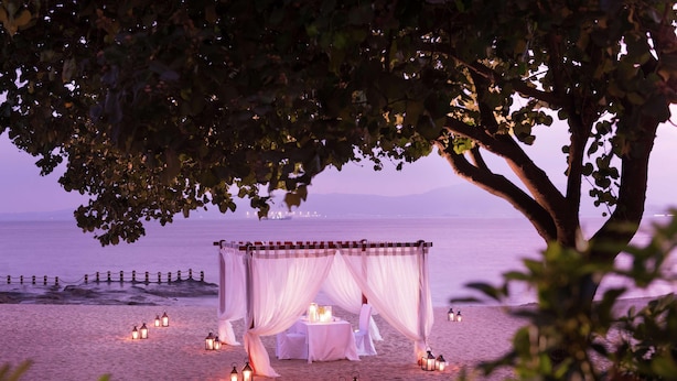 A beach setting with a canopy table under a tree, surrounded by lanterns. - Joyze Hotel Xiamen Curio Collection by Hilton (Xiamen)