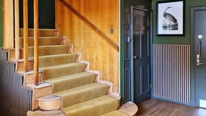 A spiral staircase with wooden steps and a handrail, leading to a landing with a door and a framed picture on the wall. - The Alyth Hotel (Blairgowrie)