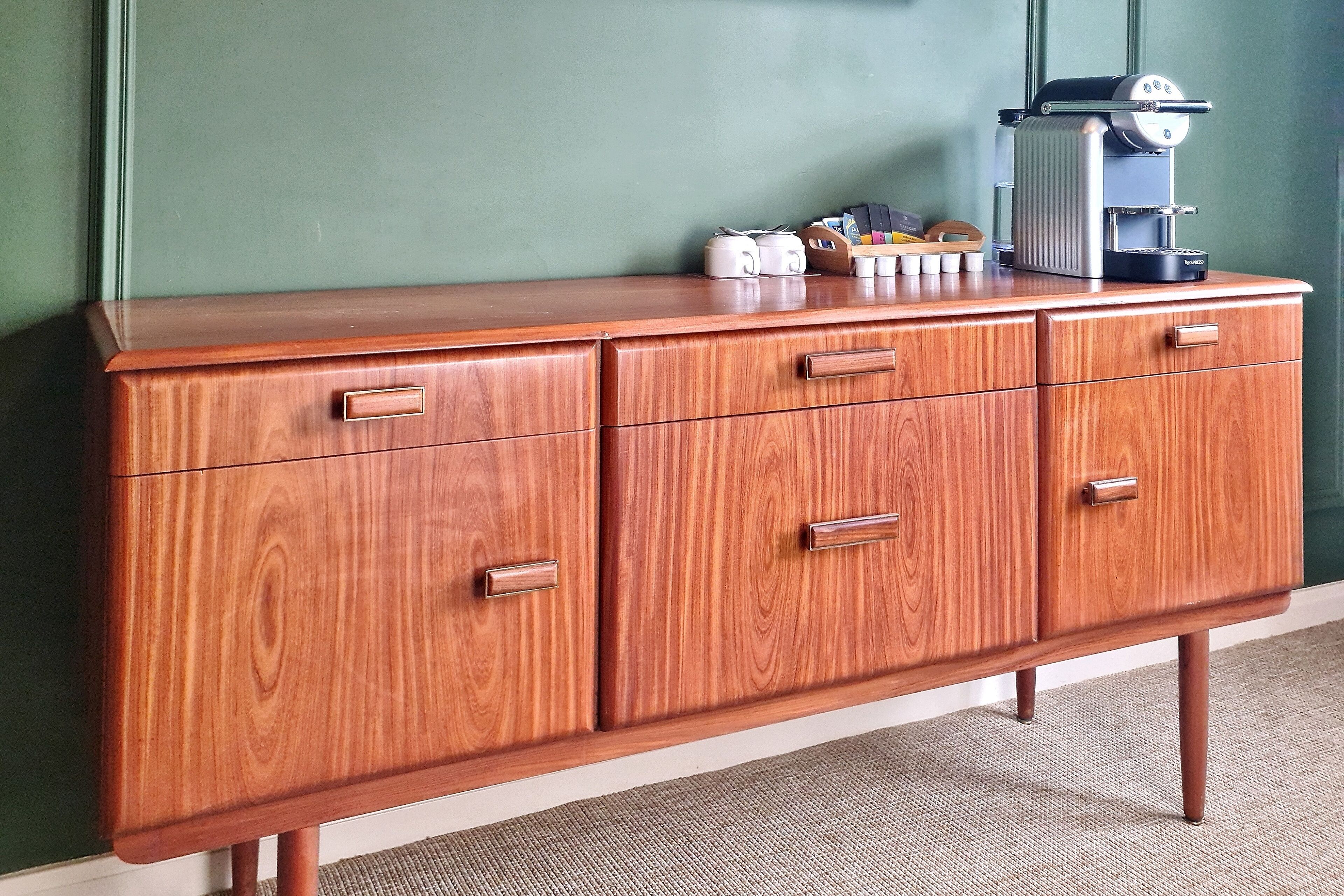 A wooden cabinet with drawers and a coffee machine on top.