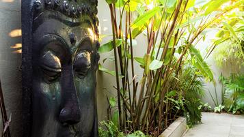 Escultura de cabeça de Buda em um vaso com plantas tropicais.