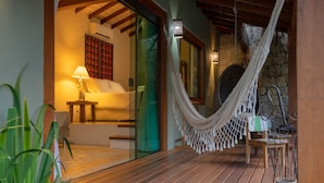 A wooden deck with a hammock, a sofa, and a lamp. - Hotel Vila Kebaya (Ilhabela)